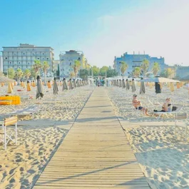 Spiaggia con ombrelloni chiusi e palme davanti a edifici