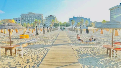 Spiaggia con ombrelloni chiusi e palme davanti a edifici