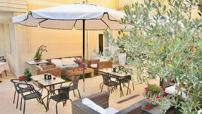 Zona pranzo all'aperto con ombrellone, sedie e tavoli in un cortile