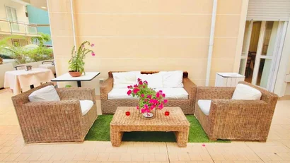Salotto esterno con mobili in rattan e fiori rosa su tavolo