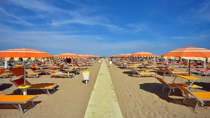 Ombrelloni arancioni e sdraio su una spiaggia sabbiosa sotto un cielo blu