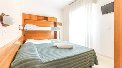 Camera con letti a castello pieghevoli e letto matrimoniale con copriletto a righe