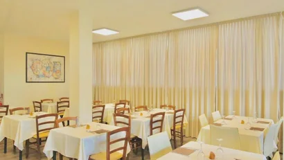 Sala ristorante con tavoli apparecchiati e sedie in legno e plastica