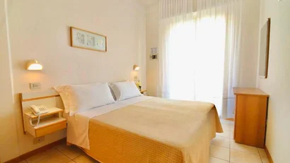 Camera d'albergo luminosa con letto matrimoniale e mobili in legno chiaro