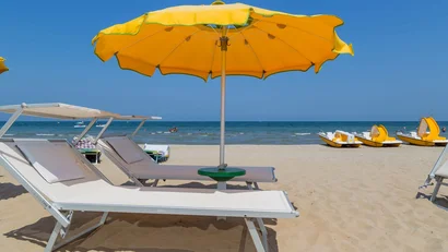 Ombrellone giallo e lettini sulla spiaggia con vista mare e pedalò