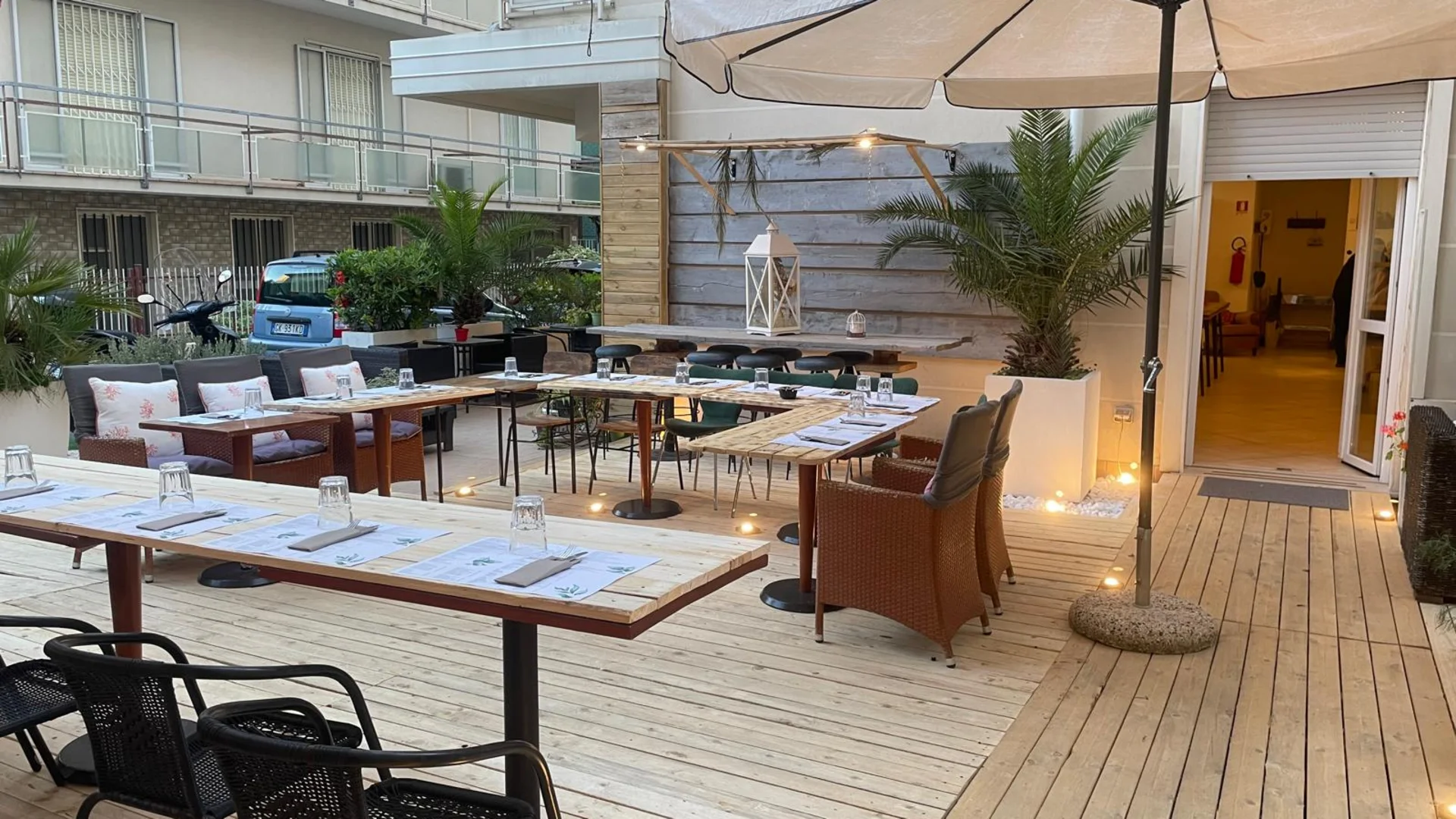 Tavoli e sedie all'aperto in un ristorante con ombrellone e luci a sospensione