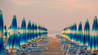 Ombrelloni azzurri chiusi in fila su una spiaggia al tramonto