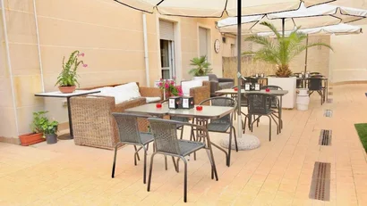 Tavoli e sedie all'aperto con ombrelloni e piante in un patio soleggiato