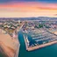 Veduta aerea del porto e della spiaggia al tramonto con la città e le montagne sullo sfondo