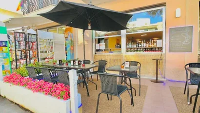 Bar con tavoli all'aperto, ombrellone nero e fiori rosa