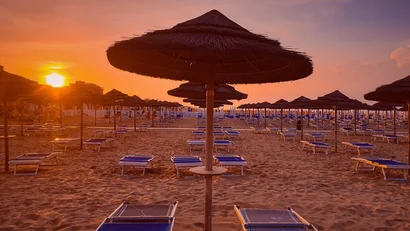 Ombrelloni di paglia e sdraio su spiaggia al tramonto